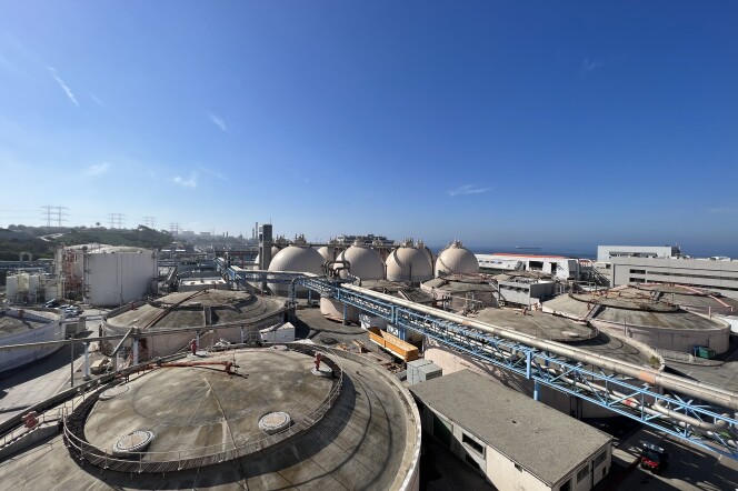 A wide angle shot overlooking a large industrial wastewater treatment plant. The ocean can be seen in the distance. 