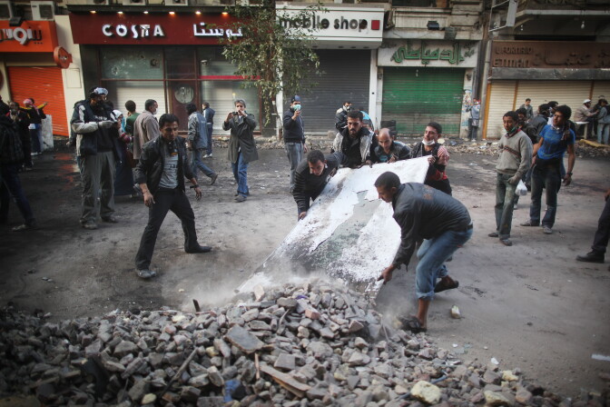 CAIRO, EGYPT - NOVEMBER 23:  Protestors clear debris from Mohammed Mahmoud Street after police withdrew on November 23, 2011 in Cairo, Egypt. Thousands of Egyptians are continuing to occupy Tahrir Square after four days of clashes with security forces despite a promise from military leaders to bring forward Presidential elections.  (Photo by Peter Macdiarmid/Getty Images)