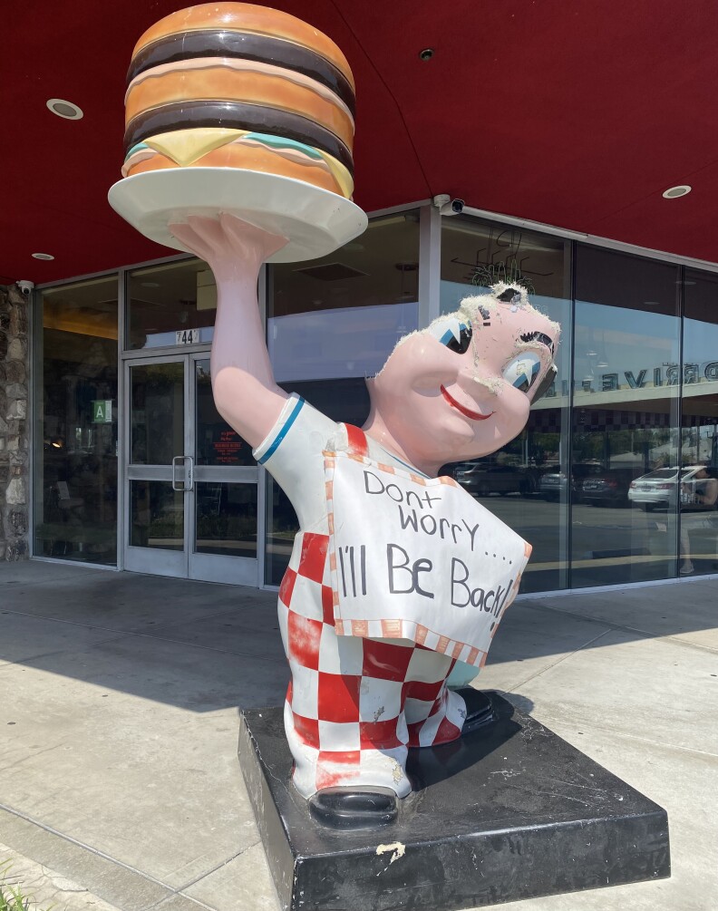 A damaged Bob's Big Boy statue stands in Downey. The top part of his head is gone and a sign on him reads: "Don't worry... I'll be back!"