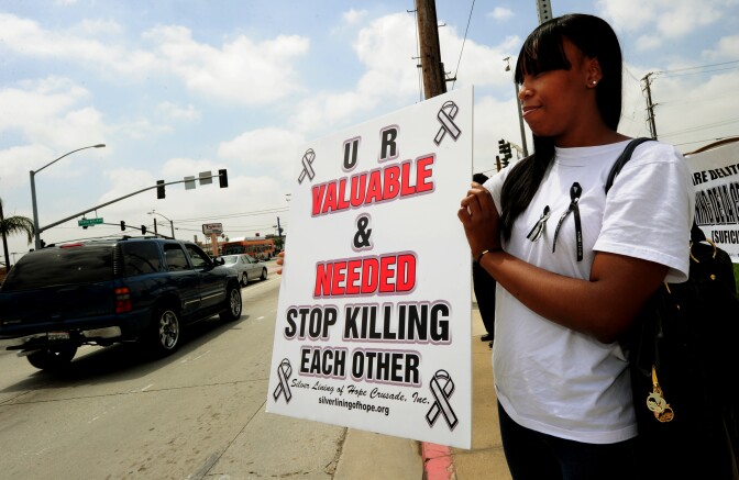 Ty'Asia Talbert who is the cousin of murdered rapper Monte "M-Bone" Talbert holds up gang peace messages during a gang intervention event in Compton, California on May 28, 2011.  Reverend Ball  belongs to the group 'Silver Lining of Hope Crusade' who claim that over 19,000 people have died in gang violence in Los Angeles over the past 30 years.     AFP PHOTO/Mark RALSTON (Photo credit should read MARK RALSTON/AFP/Getty Images)