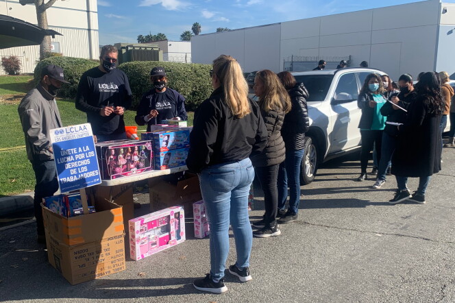 People stand outside of Jon Donaire's building for a toy drive. There are toys on a table, and a sign that reads "Unete a la lucha por los derechos de los trabajadores."