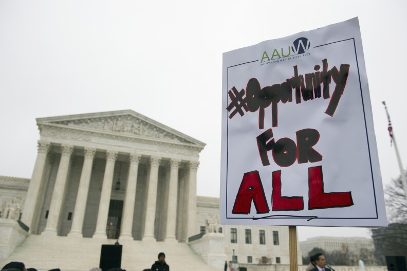 A demonstrator with the American Association of University Women (AAUW) holds a sign outside the Supreme Court in Washington, Wednesday, Dec. 9, 2015, as the court heard oral arguments in the Fisher v. University of Texas at Austin affirmative action case. (AP Photo/Cliff Owen)