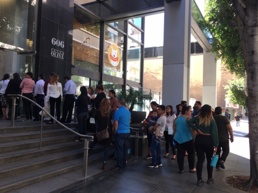A line of people outside a building on a city street.