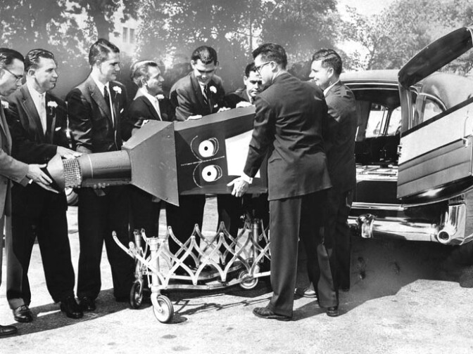 "Deprived of a last chance at smog-making, an incinerator is loaded into a hearse for a ride to the dump. Pallbearers are, left to right: A. Edsel Curry, President of Junior Chamber of Commerce; S. Price Scot, Vice President of Junior Chamber; John R. Glass; Victor Etienne; Lynn H. Montoy Jr. ; Karl R. Davis Jr.; Roy Irvin and Delbert Campbell. All backyard burners will be illegal as of October 1, when Air Pollution Control District's ban on residential incinerators comes effective. Many of the incinerators have been converted to outdoor barbecues by owners. Photo dated September 30, 1957." 