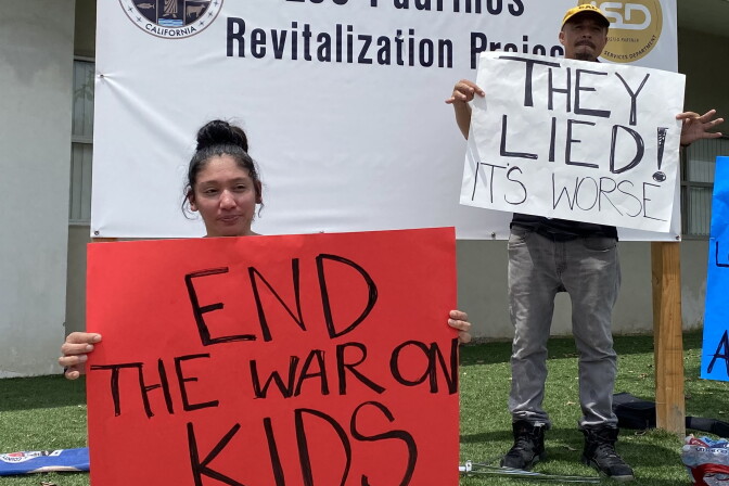 A protester holds a sign that reads 'End the War on Kids' 