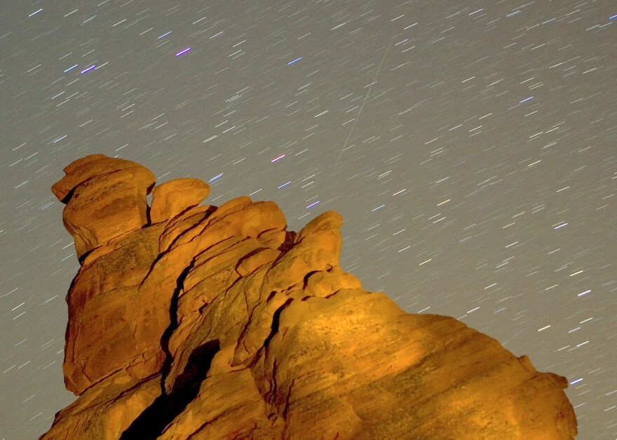 VALLEY OF FIRE STATE PARK, NV - DECEMBER 14: A Geminid meteor streaks diagonally across the sky against a field of star trails over one of the peaks of the Seven Sisters rock formation early December 14, 2007 in the Valley of Fire State Park in Nevada. The meteor display, known as the Geminid meteor shower because it appears to radiate from near the star Castor in the constellation Gemini, is thought to be the result of debris cast off from an asteroid-like object called 3200 Phaeton. The shower is visible every December. (Photo by Ethan Miller/Getty Images)