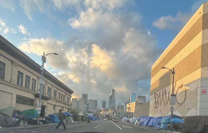 Makeshift tents line with both sides of a city street with tall skyscrapers visible in the background.