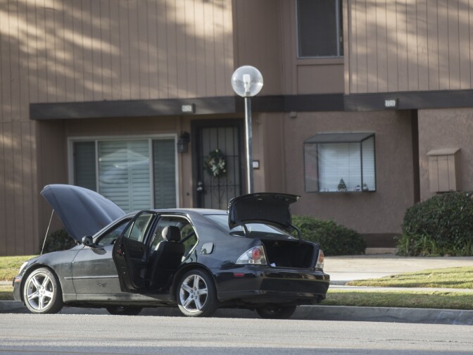 N Center Street between Pine Street and N Center Place remains closed as authorities continue to search a Redlands home on Thursday morning, Dec. 3, 2015 following Wednesday's mass shooting at in San Bernardino. The hood, doors and trunk of a car remain open outside the residence.
