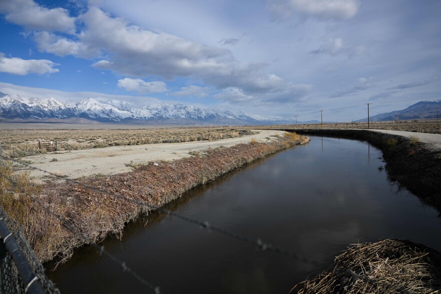 Water flowing through an aqueduct with snow capped mountains off in the background.