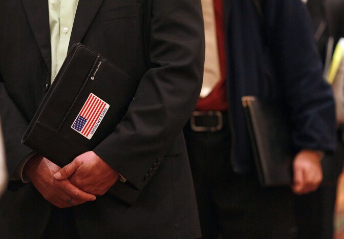 SAN FRANCISCO, CA - NOVEMBER 09:  A job seeker holds an organizer with an American flag sticker on it as he waits in line to meet with a recruiter during the San Francisco Hire Event job fair on November 9, 2011 in San Francisco, California.  The national unemployment rate dipped this past month to 9 percent in October after employers added 80,000 jobs.  (Photo by Justin Sullivan/Getty Images)