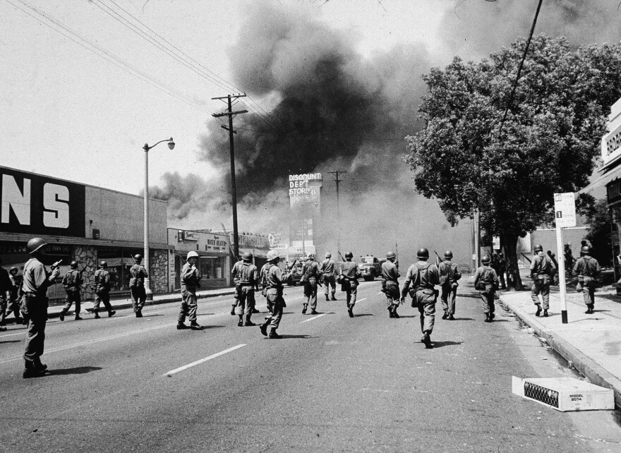 Armed National Guardsmen march toward smoke on the horizon during the street fires of the Watts riots, Los Angeles, California, August 1965. (Photo by Hulton Archive/Getty Images)