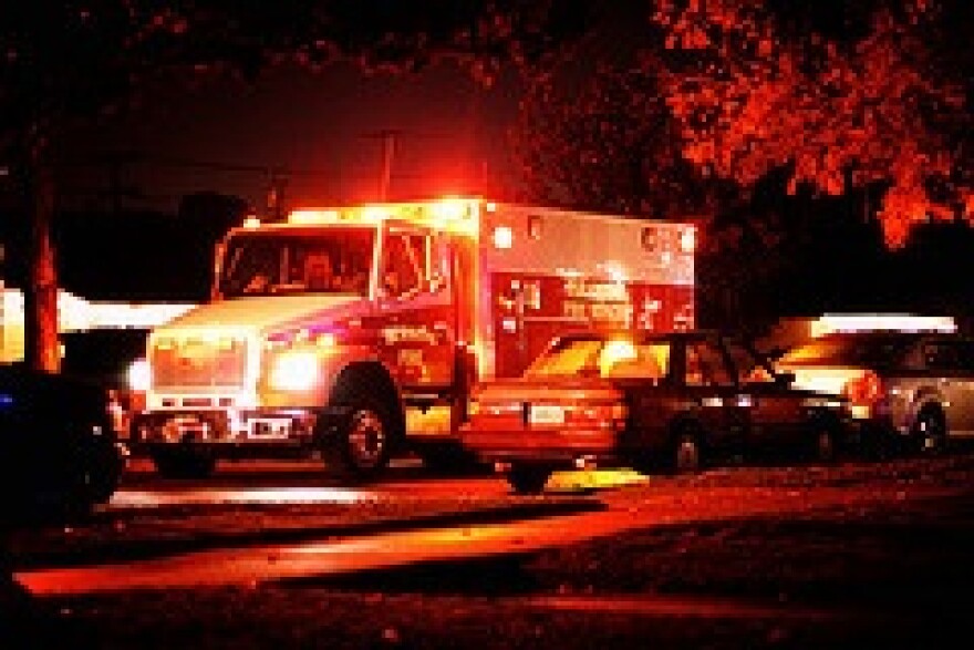 An ambulance with flashing lights drives down the street at night.