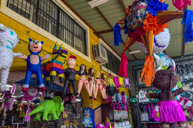 A party store from the outside, full of colorful piñatas hanging from the ceiling. 