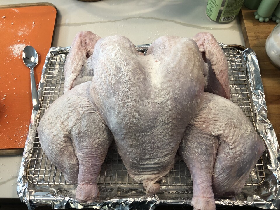 A turkey is flatted out on a metal grid over a tray