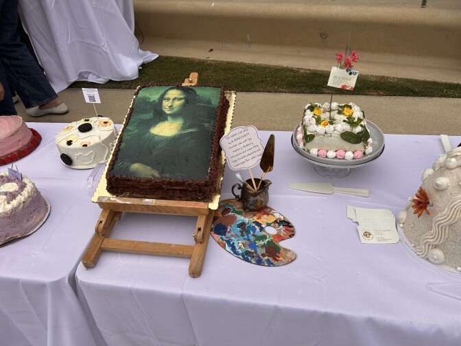 A cake with an image of the Mona Lisa on top of it. Next to that are other cakes.