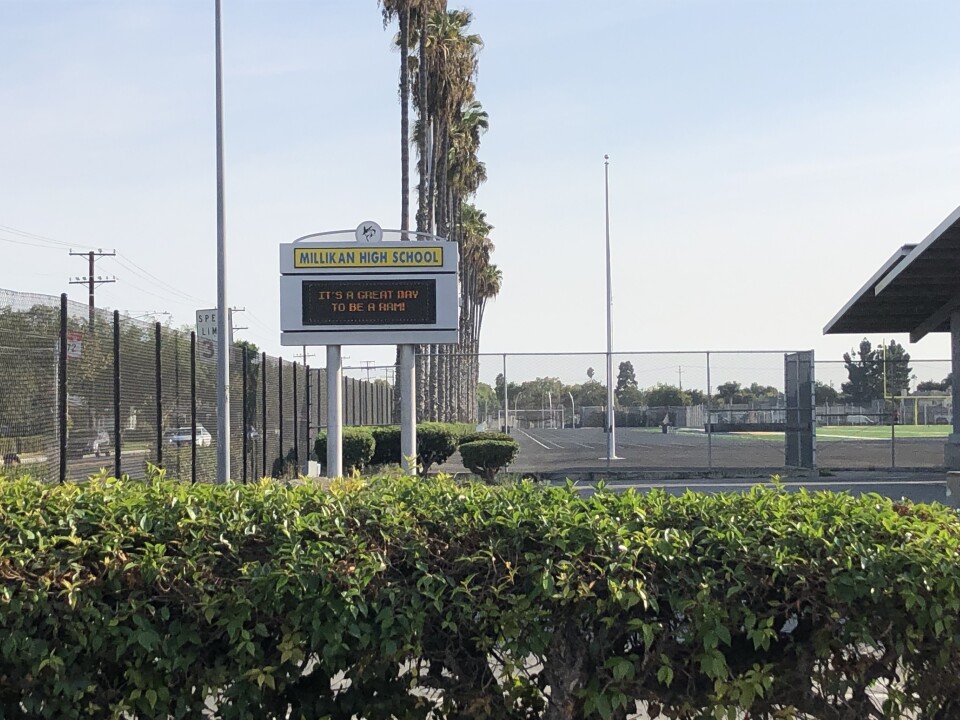 A photo of a campus sign from Millikan High School next to a parking structure.