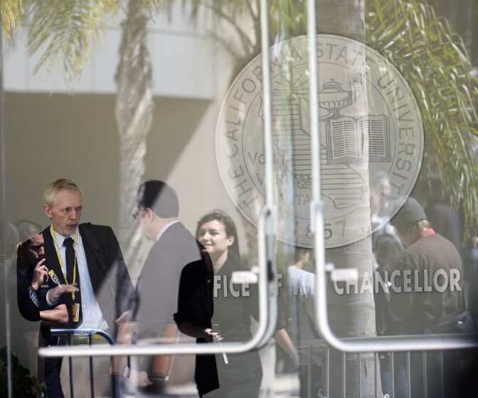 Demonstrators are reflected in windows at the main entrance to the CSU Chancellor's office in Long Beach Wednesday. Students and activists were showing their opposition to a systemwide $280 per semester "Student Success Fee."