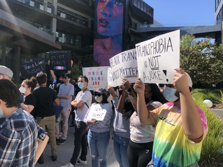 An image of a group of several protesters outside the Netflix office building. They were rallying against the new Dave Chappelle special and one protester held a sign that read, "Transphobia is not a joke."