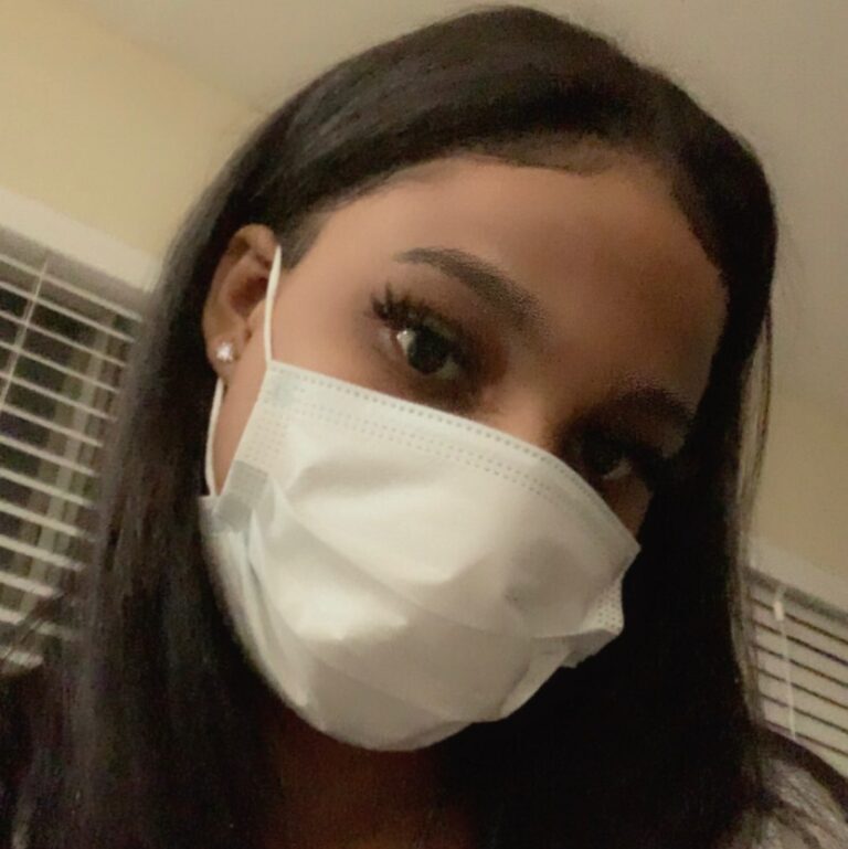 A young woman wearing a mask takes a selfie.
