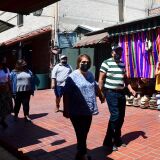 Face masks remain worn as people walk along Olvera Street in Los Angeles on June 14, 2021, one day before the state full reopening of its economy since the first statewide shutdown in March 2020 due to the coronavirus pandemic. - California is removing nearly all pandemic restrictions on June 15, with no mandatory capacity restrictions or social distancing requirements for those who have been vaccinated. (Photo by Frederic J. BROWN / AFP) (Photo by FREDERIC J. BROWN/AFP via Getty Images)