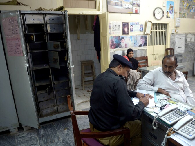 A Pakistani policeman speaks to an employee next to an emptied safe the day after the Sunday robbery at the Edhi Foundation charity in Karachi.Gunmen took cash and gold worth more than $1 million.