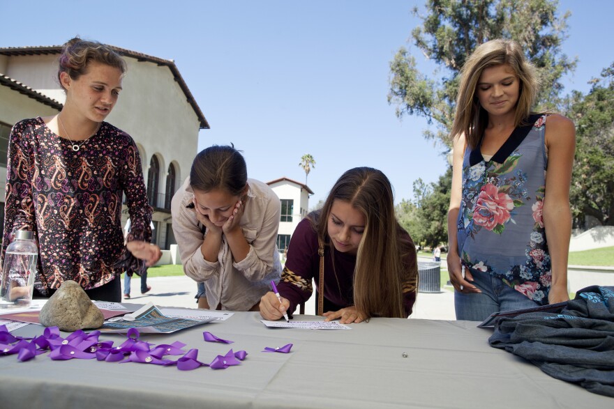 Sofia Schugar, left, Natalie Sharp, Lenox Peterson and Isabel Annino stop at the domestic violence awareness table at Occidental College to write phrases in support of sexual assault awareness on campus. They are cross-country running recruits who will attend Occidental next year. "A girl going to college shouldn't have to worry about dating violence," Sharp said. "She should only have to worry about her education."