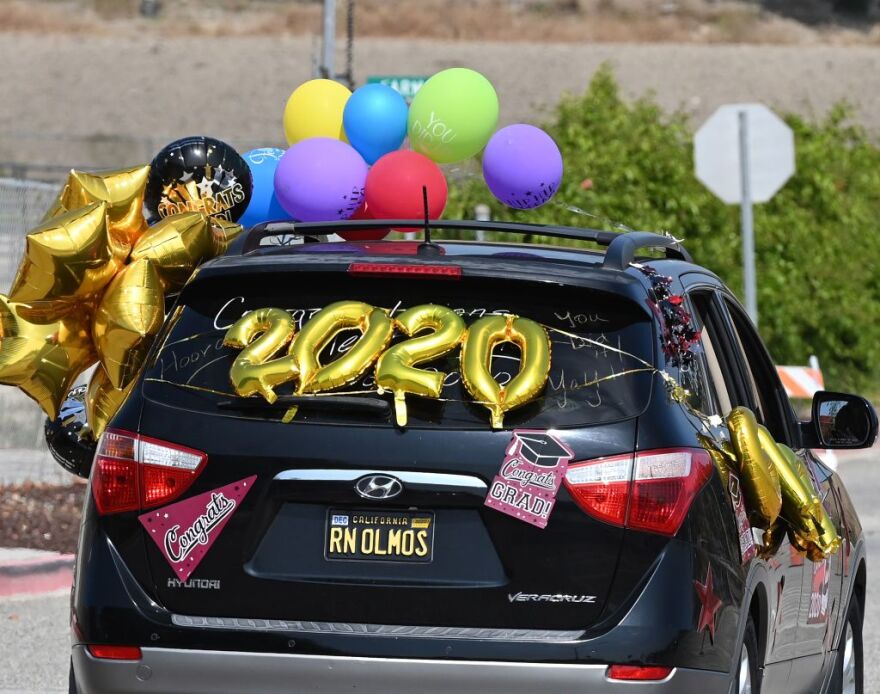 Graduating students from Mount San Antonio College receive their diplomas through their car window at a drive-thru commencement ceremony for the "Resilient Class" of 2020, which includes more than 650 students, June 18, 2020 in Walnut, California. - The college design the car-based ceremony to comply with Los Angeles County and California state COVID-19 gathering restrictions. (Photo by Robyn Beck / AFP) (Photo by ROBYN BECK/AFP via Getty Images)