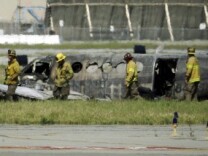Firefighters view the wreckage of a twin-engine Beechcraft King Air airplane where it crashed and burned on takeoff from Long Beach, Calif., Airport on March 16, 2011.