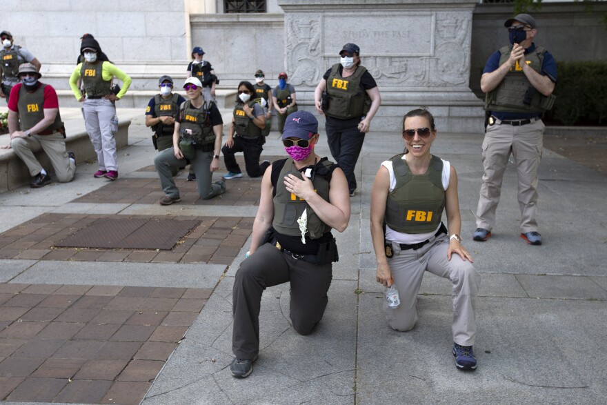 Multiple people in FBI flak jackets are pictured kneeling.