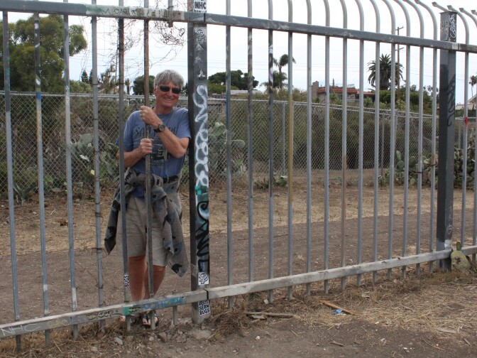 Graham Robertson shows the hole in the fence that makes trespassing easy into the Sunken City.