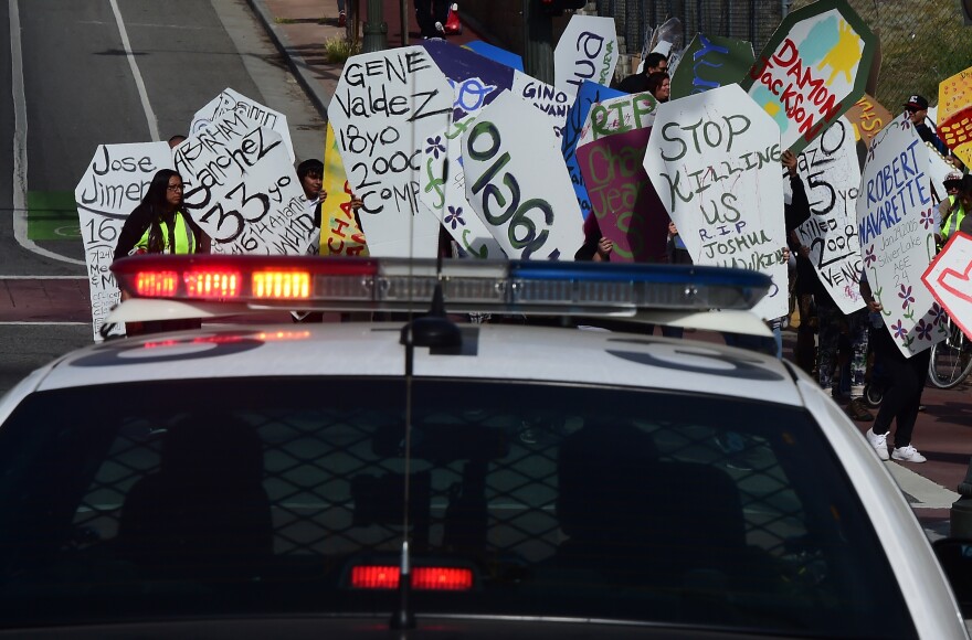 Law-enforcement personel watch from their vehicle as demonstrators walk along a street in east Los Angeles on April 7, 2015, carrying makeshift coffins during the "Remember Me" march for people who have been killed by law enforcement. Over 617 people have been killed by LAPD since 2000, according to the organization youth4justice.  AFP PHOTO / FREDERIC J. BROWN        (Photo credit should read FREDERIC J. BROWN/AFP/Getty Images)