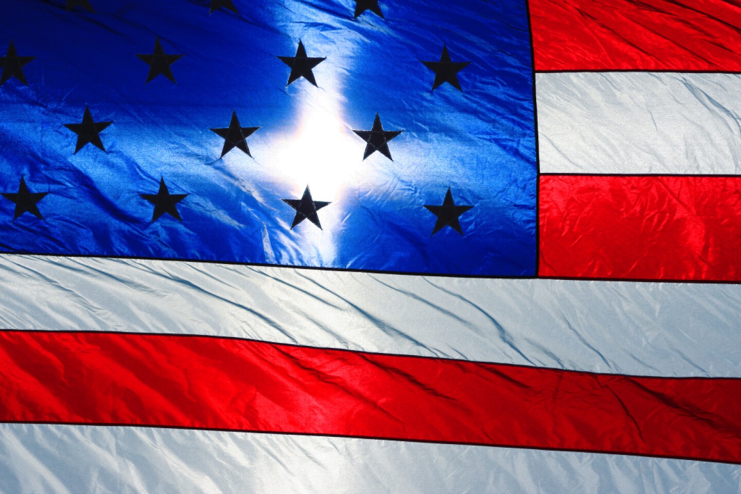 A flag for free download and use. The sun is shining brightly in the morning sky, through our American Flag.