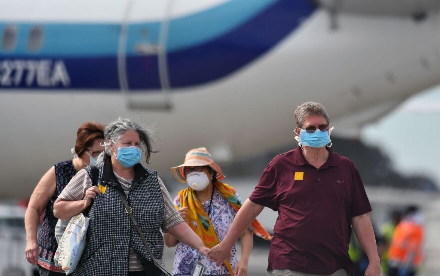 Medical Personnel help load passengers from the Grand Princess cruise ship onto airplanes at Oakland International Airport in Oakland, California on March 10, 2020. - The first passengers were taken ashore from a coronavirus-hit cruise ship that docked at California's port of Oakland on March 9, 2020, with the infected "being dealt with in proper isolation," said US Vice President Mike Pence. The Grand Princess arrived in the San Francisco Bay after days stranded at sea with 21 confirmed coronavirus infections among more than 3,500 passengers and crew. (Photo by Josh Edelson / AFP) (Photo by JOSH EDELSON/AFP via Getty Images)