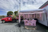 Photo of a truck next to a pop-up business. The pop-up business had a banner titled "Ooey Gooey Cinnamon Rolls." Another banner, on top of a table, has a label saying "The Little Sugarplum."
