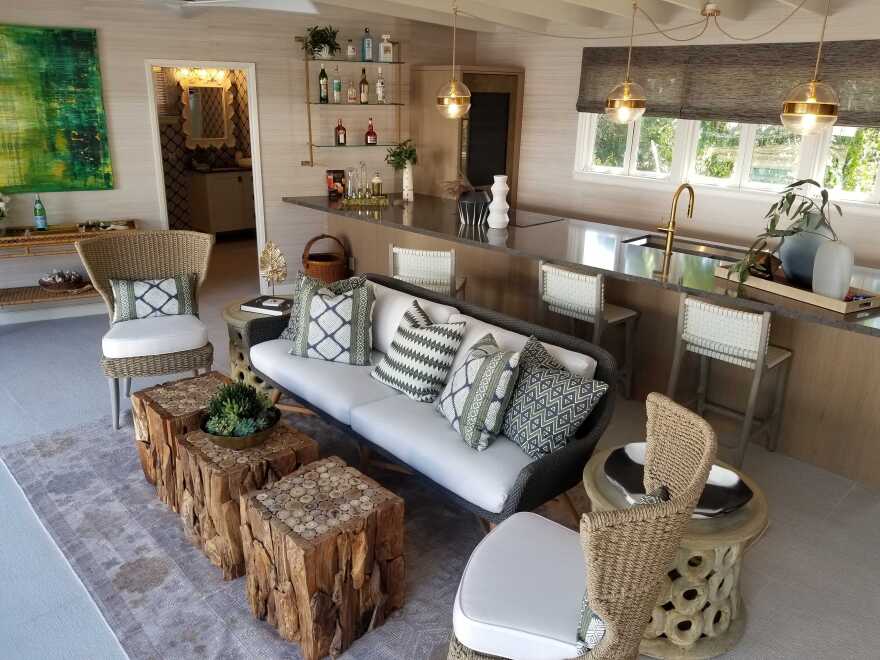 A white sofa with decorative pillows on top placed in front of a long kitchen island.