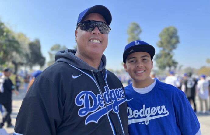 A man in his early 50s poses with a young teenage boy. Both are wearing Dodgers jerseys.