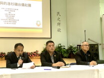Three middle-aged Taiwanese American men sit at a table holding a news conference. 