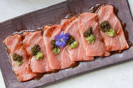 Slices of sashimi served on a clay slab. 