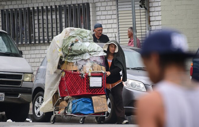 A homeless woman pushes her cart full of belongings along a street in Los Angeles, California on August 25, 2015. According to a report released today by the Economic Roundtable, a nonprofit research group in Los Angeles, some 13,000 people tumble into homelessness every month in Los Angeles County, where the latest official count of the homeless found 44,000 people living along county streets during a three-day period in January, a increase of 12%  in two years.  AFP PHOTO /FREDERIC J.BROWN        (Photo credit should read FREDERIC J. BROWN/AFP/Getty Images)