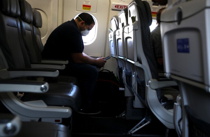 HOUSTON, TEXAS  - MAY 11: A passenger looks at his phone while waiting aboard a United Airlines plane before taking off from George Bush Intercontinental Airport on May 11, 2020 in Houston, Texas. Air travel is down as estimated 94 percent due to the coronavirus (COVID-19) pandemic and major U.S. airlines are taking a major financial hit with losses of $350 million to $400 million a day and nearly half of major carriers airplanes are sitting idle. (Photo by Justin Sullivan/Getty Images)
