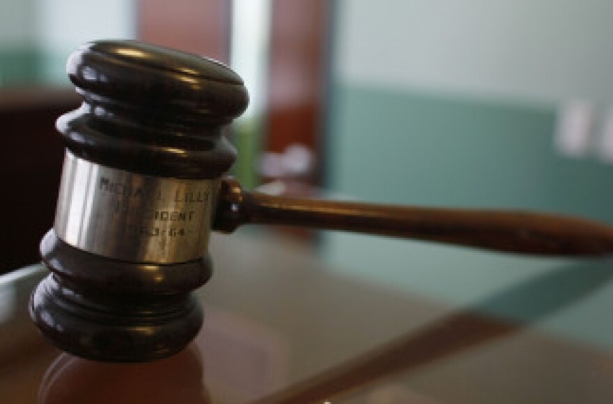 A judge's gavel rests on top of a desk in a courtroom.