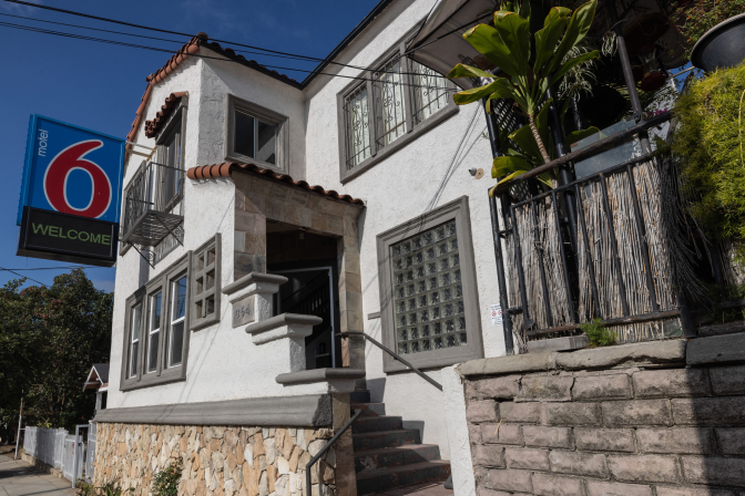 A two-story Spanish style home with a large Motel 6 sign attached to it