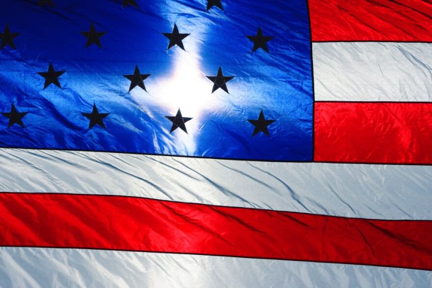 A flag for free download and use. The sun is shining brightly in the morning sky, through our American Flag.