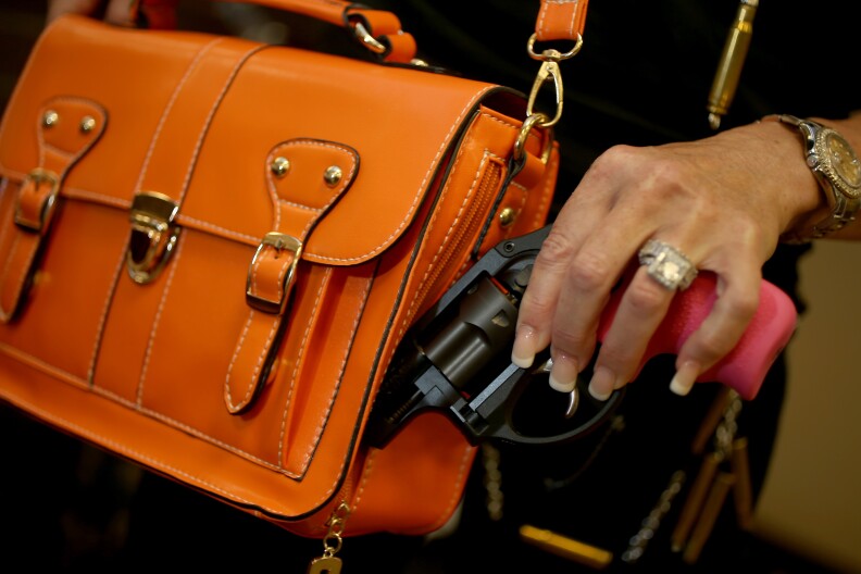 Susan Kushlin poses with a concealed-carry handbag that her company, Gun Girls, Inc., created for women that enjoy guns on October 21, 2013 in Boca Raton, Florida. 