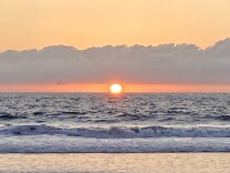 sun sets into the sea, making horizon orange 