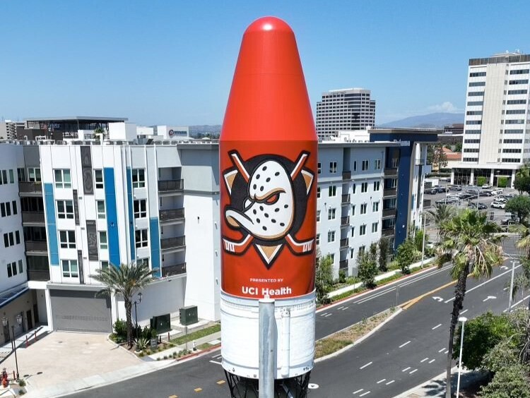 A single rocket engine is covered in orange and shows a duck-shaped hockey mask on top of two crossing hockey sticks.
