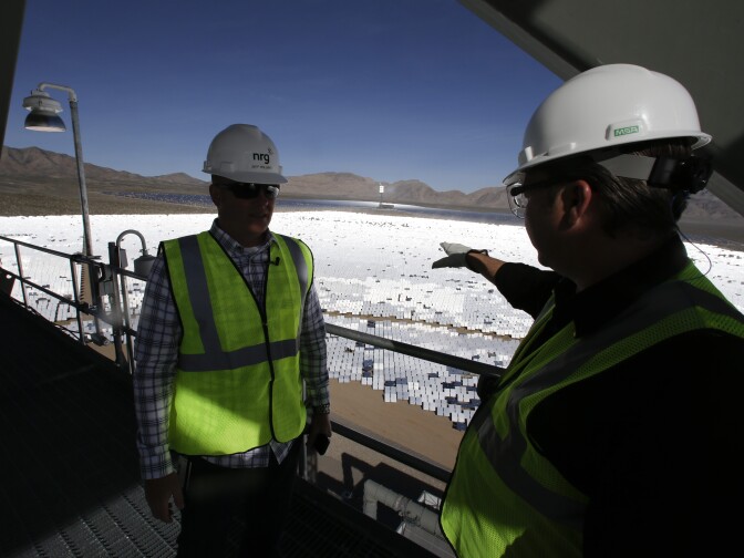 Jeff Holland, left, talks with Noel Hanson  near a boilers that sit on 459-foot towers Tuesday, Feb. 11, 2014 in Primm, Nev. The Ivanpah Solar Electric Generating System, sprawling across roughly 5 square miles of federal land near the California-Nevada border, will be opened formally Thursday after years of regulatory and legal tangles. (AP Photo/Chris Carlson)