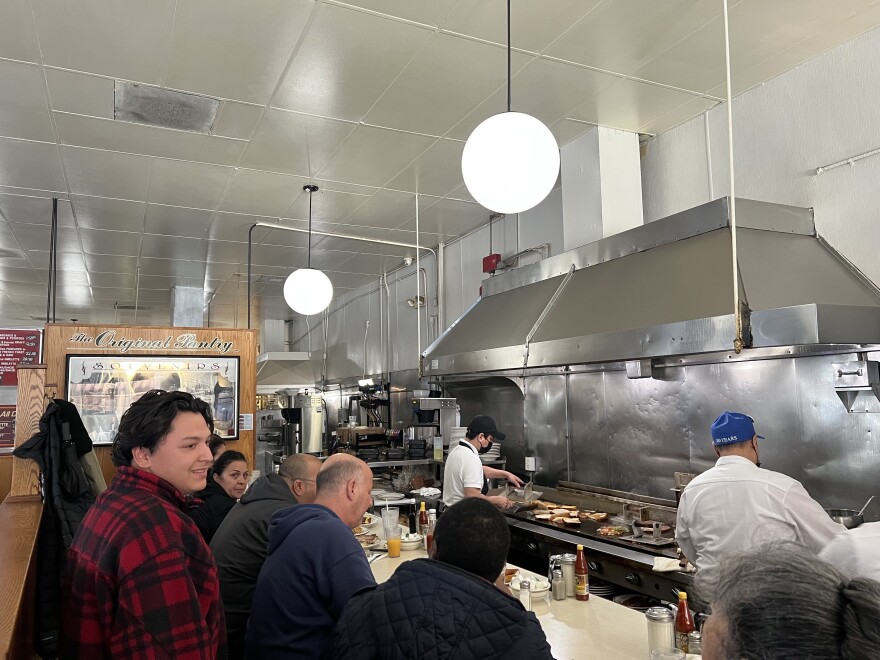 Customers sitting inside a diner as food is being prepared