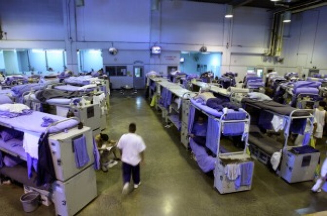 An inmate at the Mule Creek State Prison walks near the bunk beds in a gymnasium that was modified to house prisoners in Ione, Calif., on Aug. 28, 2007. The Mule Creek State Prison has had to modify several facilities to make room for an increasing number of inmates.