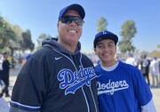 A man in his early 50s poses with a young teenage boy. Both are wearing Dodgers jerseys.